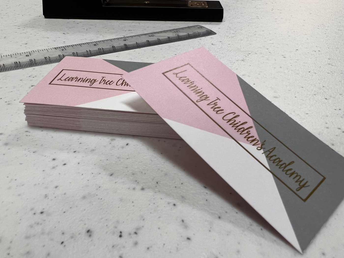 A stack of pink, white and gray business cards for a children's academy